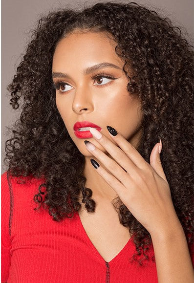 A woman posing revealing her fingers in her left-hand place in her chin showing Ardell Nail Addict Artificial Nail