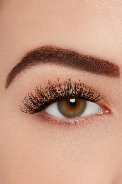Close-up of eye with Ardell strip lashes, showcasing full, wispy volume and natural curl on a brown-eyed model.